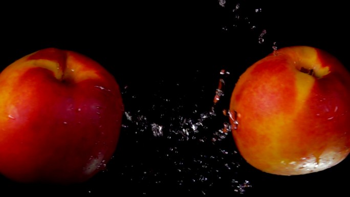 两个成熟的桃子在黑色背景上碰撞