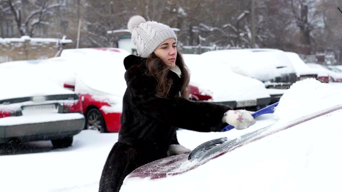 女孩在雪中清洗车。