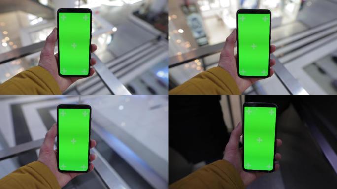 商场电梯中男性手持带绿色屏幕的智能手机