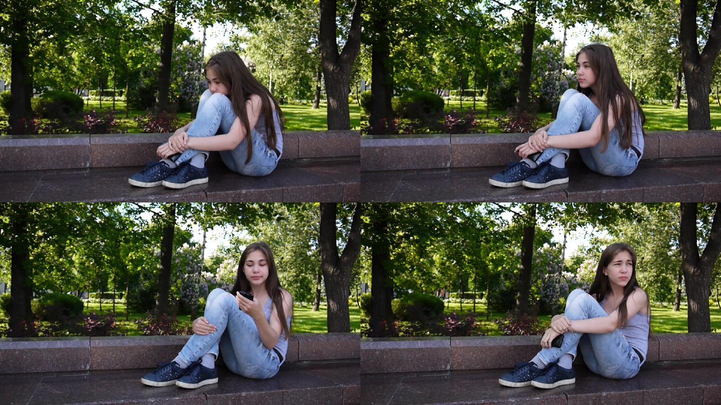 可爱的少女坐在公园里看电话，等电话。