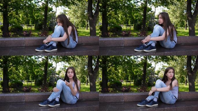 可爱的少女坐在公园里看电话，等电话。