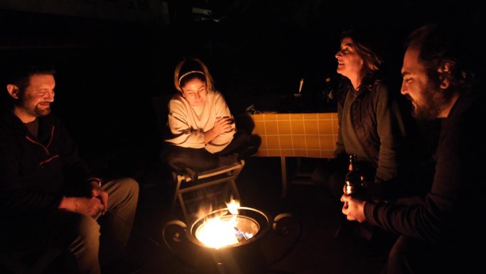 夜晚，两男两女坐在后院的火坑旁聊天。