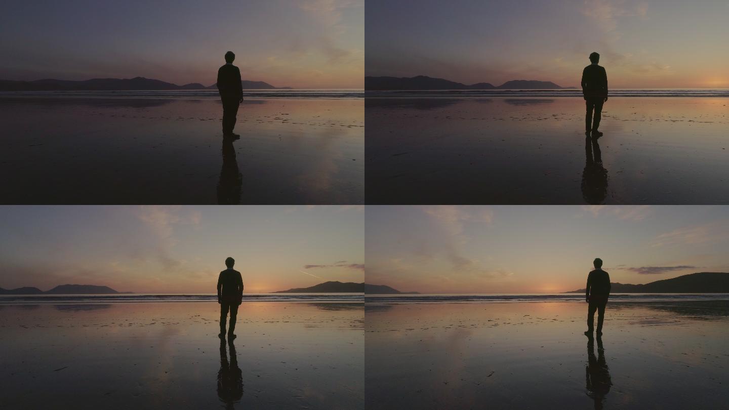 日落时一名男子站在海边的镜头