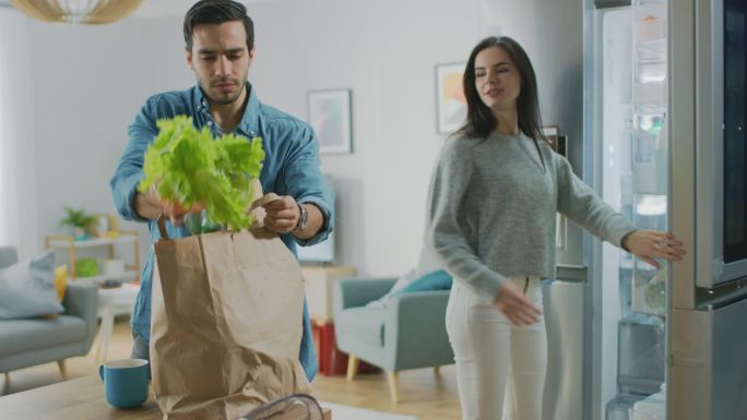 年轻夫妇带着纸袋里的新鲜食品来到厨房。