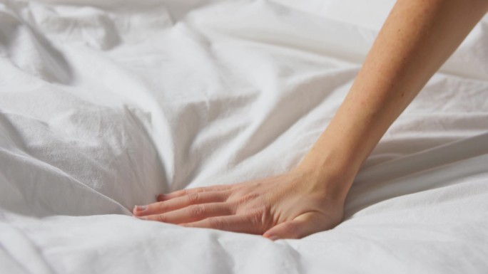 一名妇女触摸着覆盖着毯子的床