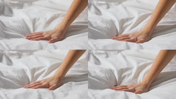 一名妇女触摸着覆盖着毯子的床