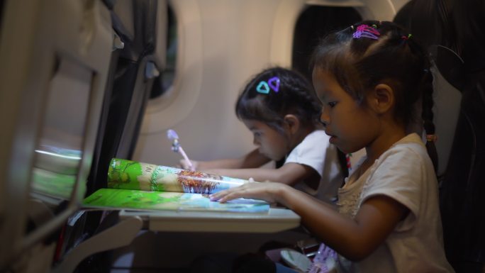 女孩在乘飞机旅行时绘画和阅读