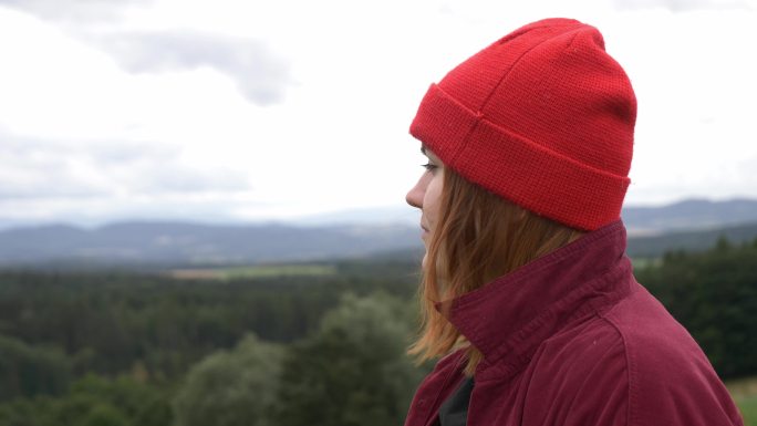 一个戴着红帽子、不化妆的年轻女孩在看山