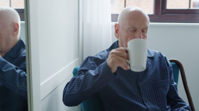 一名老人在家喝咖啡时看报纸