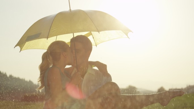 男人抱着女朋友，在雨中亲吻她。