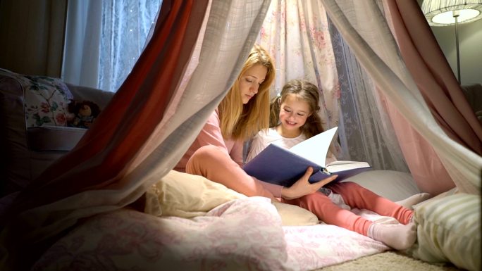 母亲和女儿在帐篷里看书