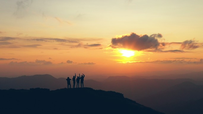 在风景如画的日落下，四个人在山顶上欢呼