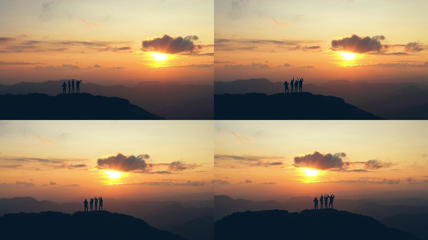 在风景如画的日落下，四个人在山顶上欢呼