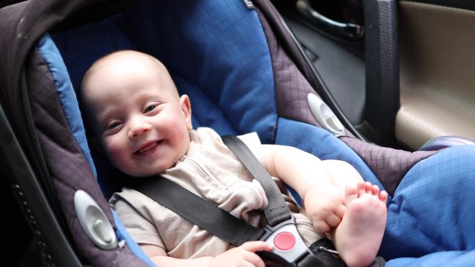 快乐的婴儿坐在车座上微笑着