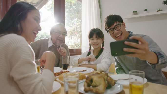 开心的家庭在餐桌上用手机视频通话