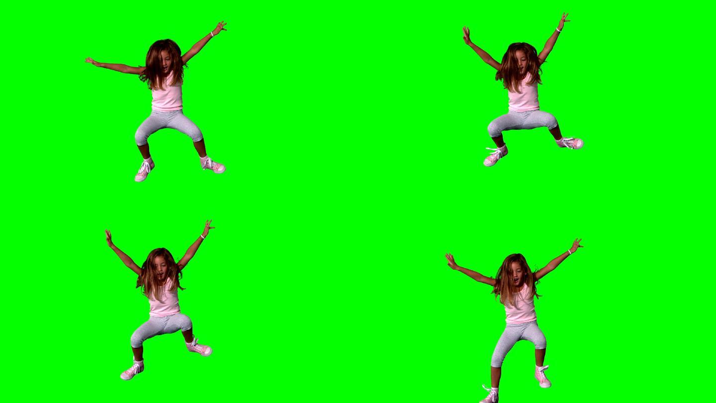 可爱的小女孩在绿色屏幕上伸展四肢跳跃