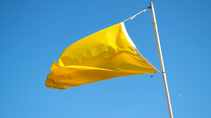海滩上的黄旗迎着蓝天迎风飘扬。