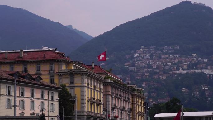 瑞士国旗。卢加诺湖建筑和蒙特布雷山。