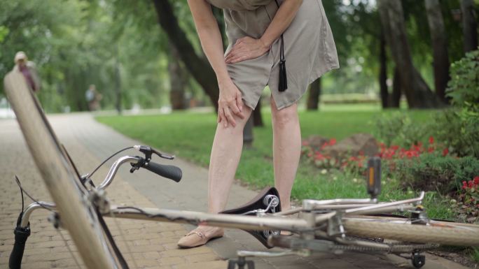 在公园里，一名妇女骑自行车摔倒受伤