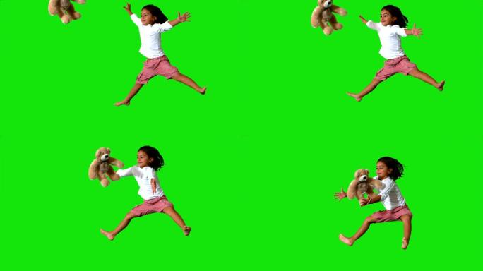 小女孩在绿色屏幕上跳跃，抓住玩具熊