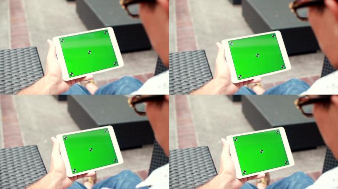 男子手持绿色屏幕的空白平板电脑