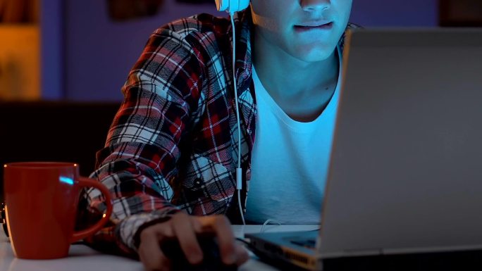 青少年在晚上戴着耳机玩网络游戏
