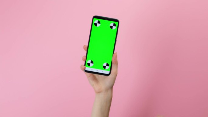 女人拿着一个绿色屏幕手机并滑动触摸屏