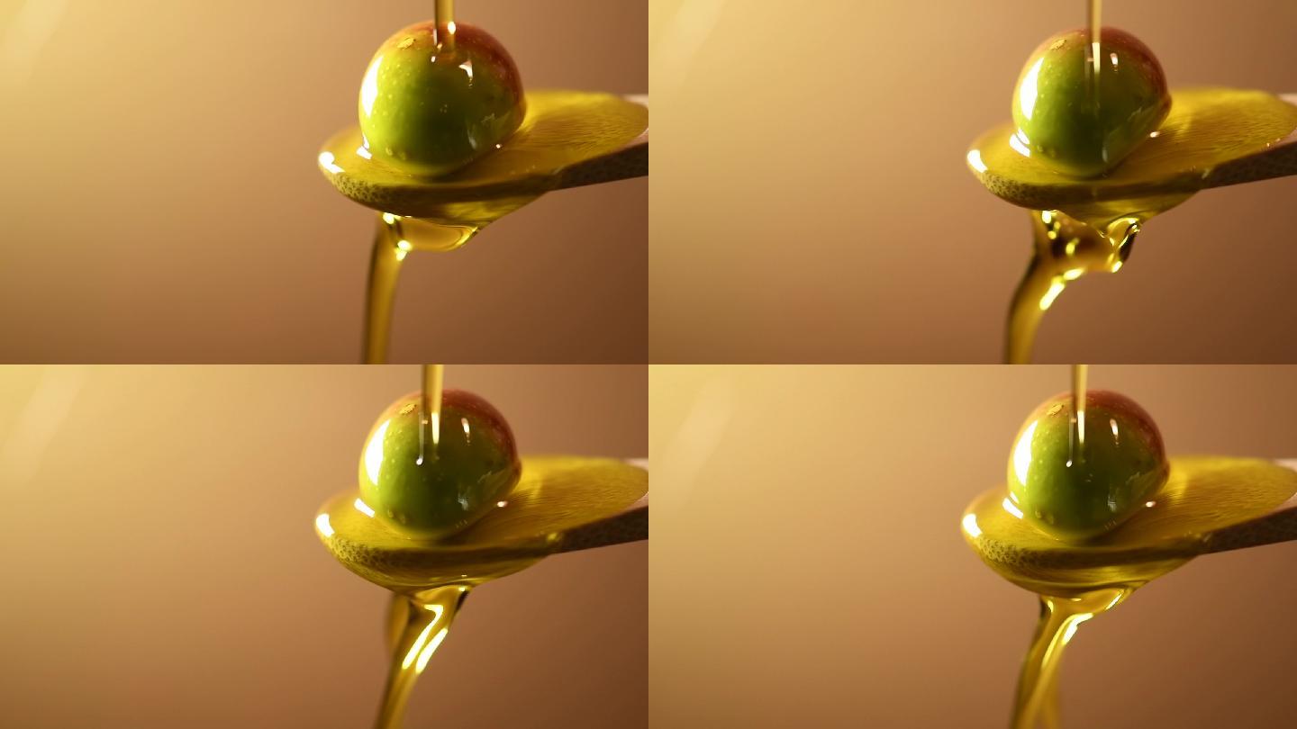 将橄榄油倒在放在勺子上的橄榄上
