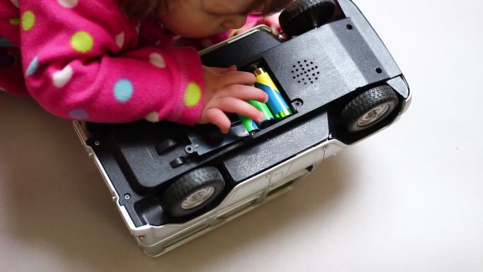 婴儿玩着一个儿童玩具，接触到里面的电池