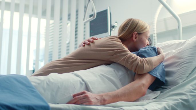 在医院里，妻子探望躺在床上康复的丈夫。
