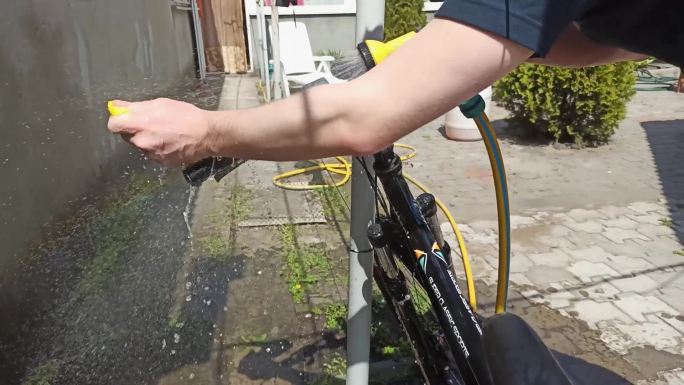 男人用抹布和水管里的水清洗他的自行车