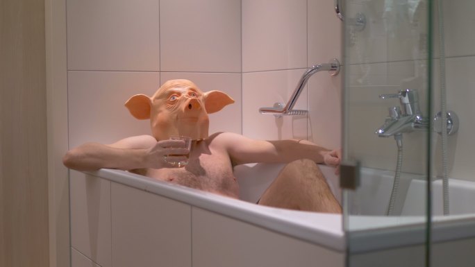 戴着猪面具的男人在浴缸里喝鸡尾酒
