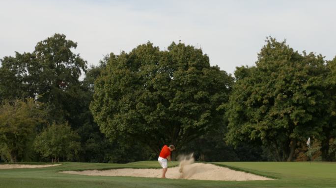 一名高尔夫球手从沙坑中打出一球。