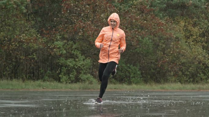 公园里穿着运动服在雨中奔跑的慢镜头