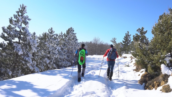 两个徒步旅行者在冬天爬山。