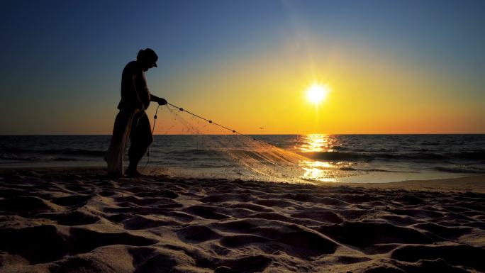 沙滩上拖拽渔网的男人