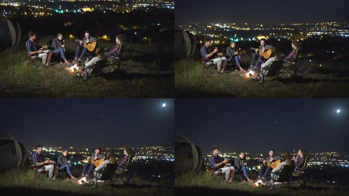 人们坐在远离城市的山坡上弹吉他