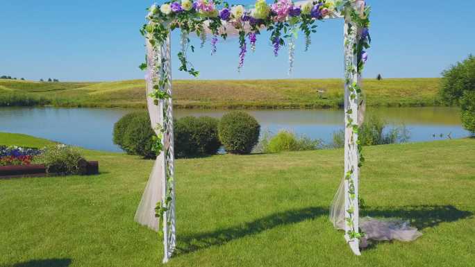 绿色草坪上鲜花点缀的婚礼拱门近景