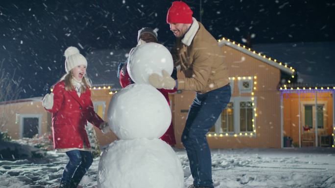 幸福的年轻家庭在后院堆雪人