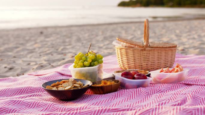 海滩毯子上的食物和野餐篮