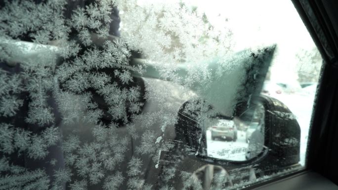 年轻女子用雪刷从车窗刮冰