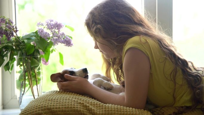 小女孩和她的小狗在窗户边休息