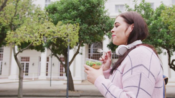 年轻的妇女吃东西和走路