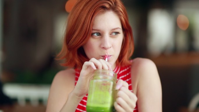 女孩喝着绿色的果汁