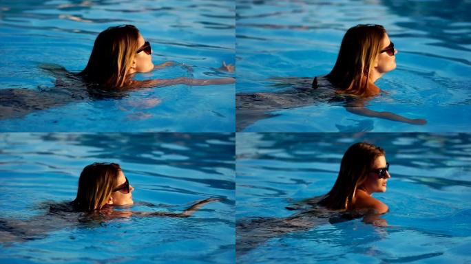 一个戴着墨镜的金发女人在泳池游泳