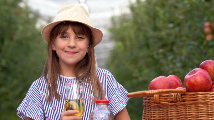 小女孩在果园里喝有机苹果汁