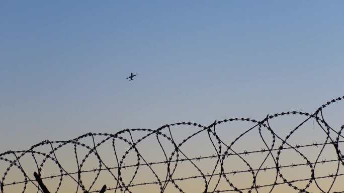 夕阳下的铁丝网上空越过飞机