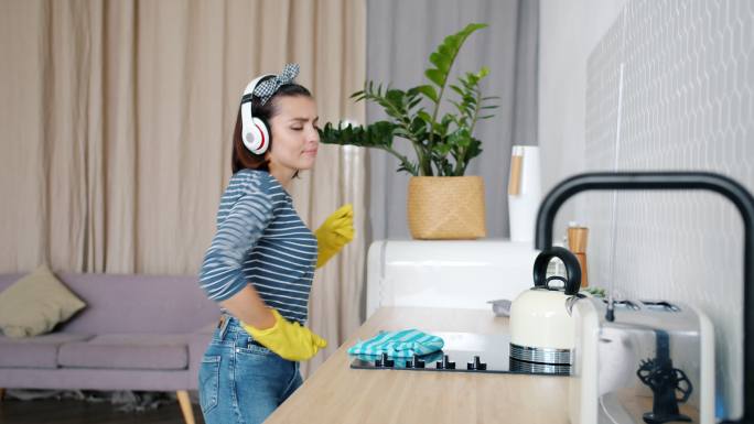 年轻女子戴着无线耳机在家打扫卫生
