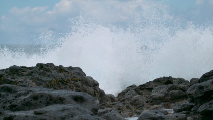 海浪席卷着岛屿上的黑色岩石