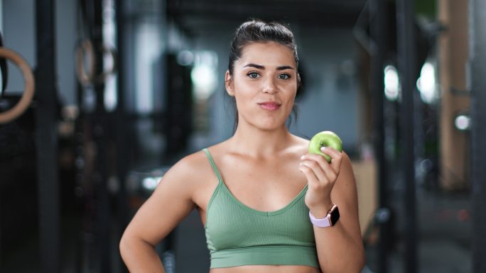 女运动员在健身房吃新鲜苹果